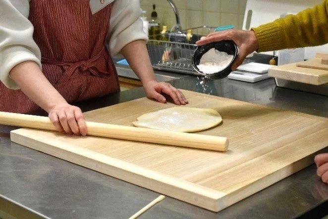うどん生地を麺棒で伸ばす様子