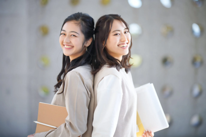 笑顔で背中合わせに立つ女性2人