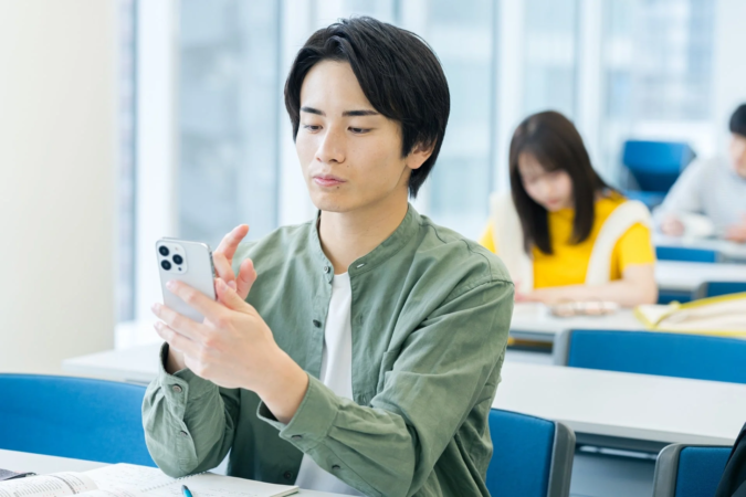 教室でスマホを操作する男性