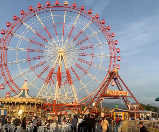 夕暮れの遊園地で楽しむ人々