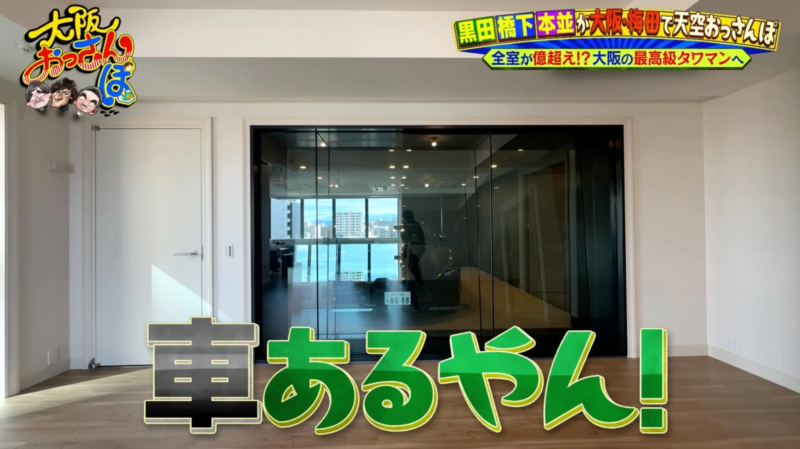 大阪・梅田の最高級タワーマンションの室内風景。高層階からの眺望が広がり、リビングの奥にはガラス越しに車が停まっているのが見える。全室1億円超えの物件を紹介するテレビ番組の一幕。