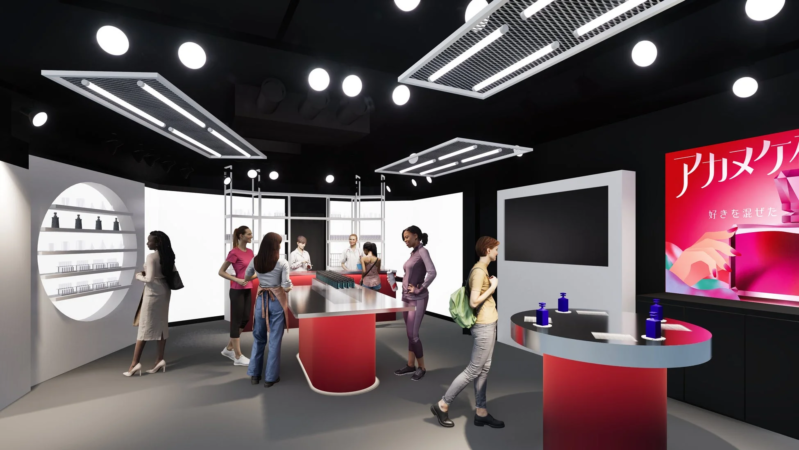 モダンなデザインの店舗または展示スペース。数人の人々が商品を見たり、会話したりしている。黒い天井と白い壁を基調とし、赤色のカウンターやディスプレイがアクセントになっている。化粧品のようなボトルが陳列されており、右奥には「アカヌケ 好きを混ぜた」と書かれた赤いポスターが見える。