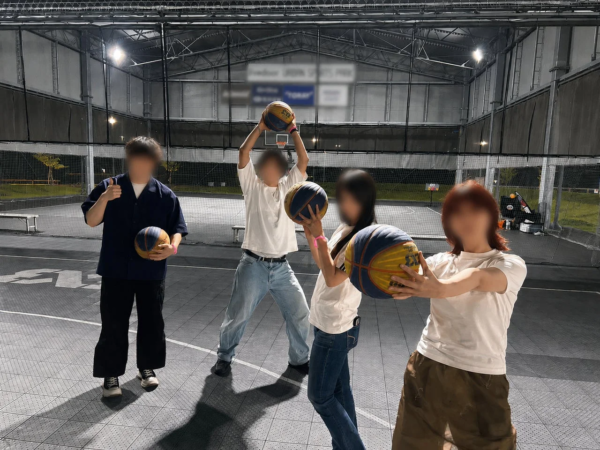 屋外のバスケットボールコートでポーズをとる若者たち
