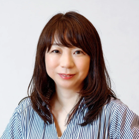 白い背景の前で、青と白のストライプシャツを着た女性のポートレート
