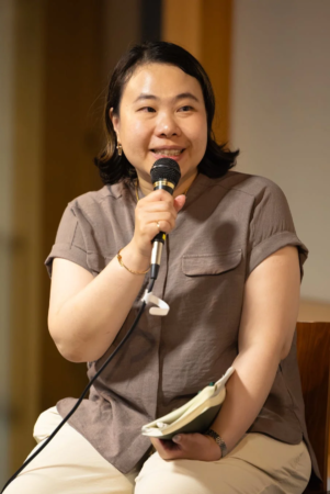 マイクを持って笑顔で話すアジア人女性のポートレート