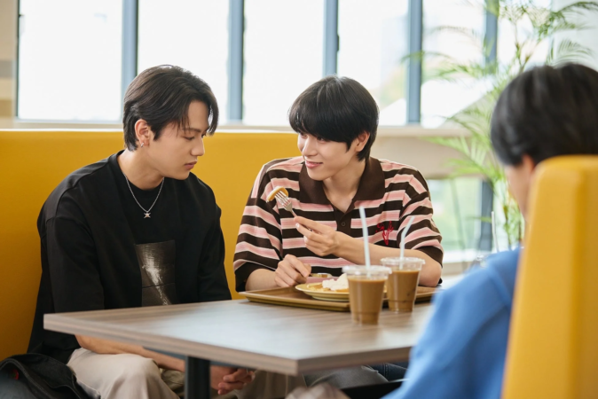 カフェのような場所で、2人の若い男性がテーブルを囲んで食事をしています